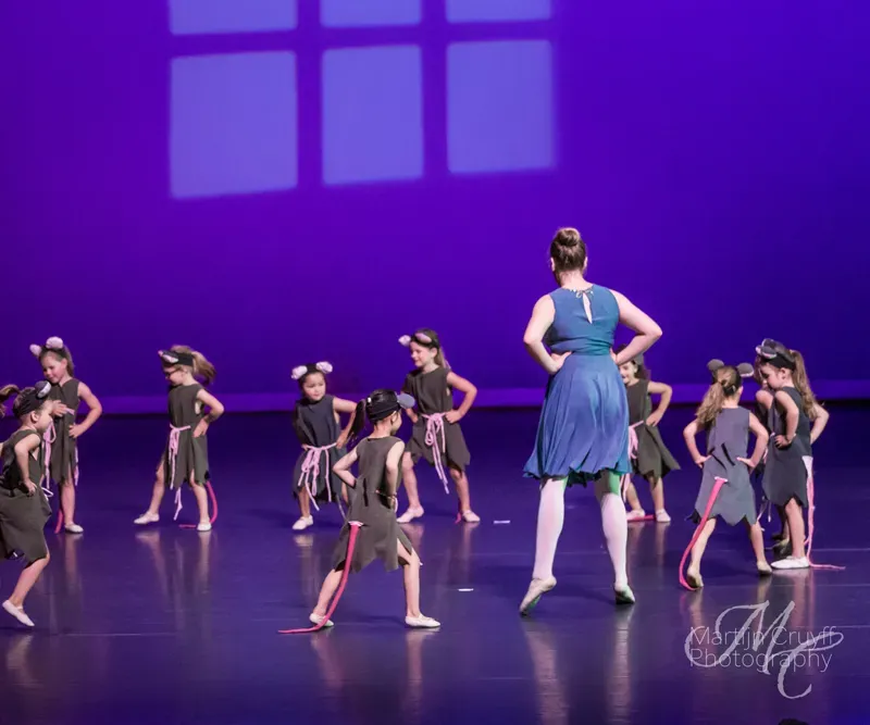 Jonge dansers en een docent tijdens een voorstelling